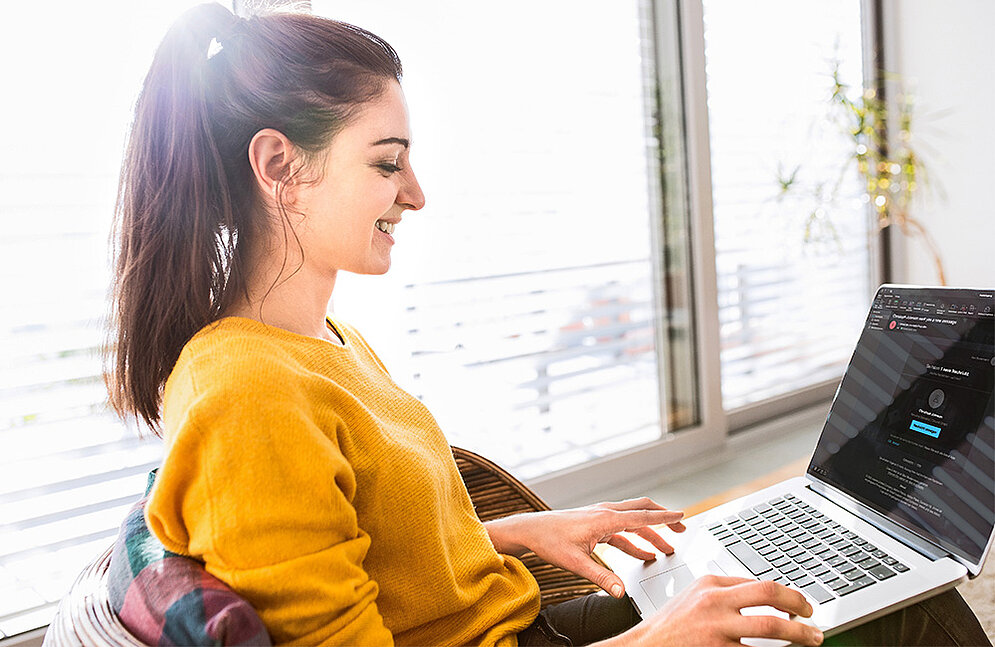 La simulación de phishing refuerza la conciencia de seguridad Una mujer feliz con un portátil en el regazo